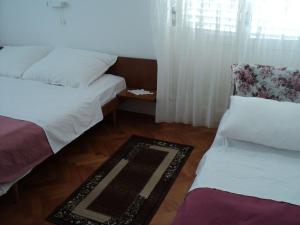 a bedroom with two beds and a rug on the floor at Rooms by the sea Banjol, Rab - 11716 in Rab