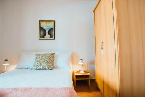 - une chambre avec un lit blanc et une armoire en bois dans l'établissement Apartments by the sea Mastrinka, Ciovo - 11711, à Trogir
