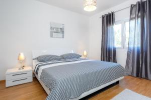 a white bedroom with a bed and a window at Holiday house with a parking space Marina, Trogir - 11767 in Marina