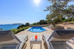 een patio met 2 stoelen en een zwembad bij Seaside luxury villa with a swimming pool Cove Siroka, Ciovo - 11749 in Trogir