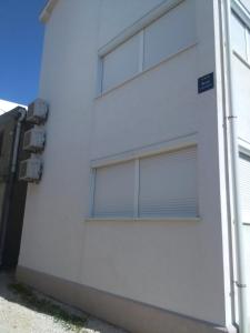 a white building with two windows with blinds at Apartments by the sea Pag - 11778 in Pag