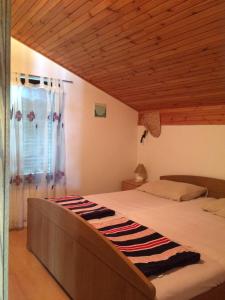 1 dormitorio con 1 cama grande y techo de madera en Apartments by the sea Ugljan - 11820 en Ugljan