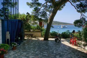 eine Person, die auf einem Roller unter einem Baum in der Nähe des Wassers sitzt in der Unterkunft Apartments by the sea Primosten - 9687 in Primošten