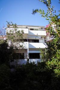 a white building with a blue awning at Apartments and rooms by the sea Podgora, Makarska - 11894 in Podgora