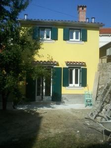 una casa gialla e verde con una sedia davanti di Holiday house with WiFi Susak, Losinj - 11911 a Susak (Sansego)