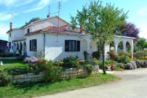 Biały dom z kwiatami przed nim w obiekcie Apartments and rooms with parking space Zambratija, Umag - 11875 w mieście Zambratija