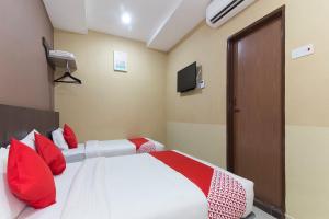 a bedroom with a bed with red pillows and a television at Silibin Times Inn Hotel in Ipoh