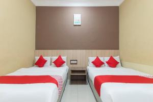 two beds in a room with red pillows at Silibin Times Inn Hotel in Ipoh