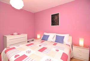 una camera da letto con pareti rosa e un letto con cuscini blu di Apartments with a parking space Rabac, Labin - 12100 a Rabac