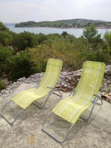 2 chaises de jardin vertes assises au sommet d'une colline dans l'établissement Secluded fisherman's cottage Radelj, Murter - 12155, à Murter