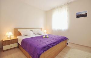 ein Schlafzimmer mit einem Bett mit violetter Bettwäsche und einem Fenster in der Unterkunft Apartments with a parking space Zadar - 12203 in Zadar