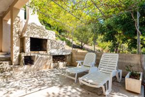a patio with two chairs and a stone fireplace at Apartments by the sea Cove Zaglav, Korcula - 12208 in Prizba +15 photos