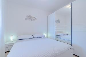 a white bedroom with a white bed and mirrors at Apartments by the sea Cove Zaglav, Korcula - 12208 in Prizba