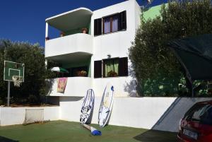 ein weißes Gebäude mit Surfbrettern, die darauf lehnten in der Unterkunft Seaside house for families with children Zatoglav, Rogoznica - 12212 in Rogoznica