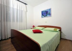 ein Schlafzimmer mit einem Bett mit einem roten Kissen darauf in der Unterkunft Seaside house for families with children Zatoglav, Rogoznica - 12212 in Rogoznica