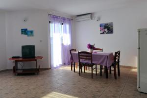 ein Esszimmer mit Tisch und Stühlen und einem Fernseher in der Unterkunft Seaside house for families with children Zatoglav, Rogoznica - 12212 in Rogoznica