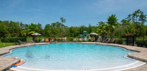 a pool at a resort with tables and chairs at Spacious 4 Bed Home near Orlando Gated Pool Access in Sanford