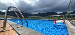 a large swimming pool with blue water and mountains at Con Son Blue Sea Hotel in Con Dao