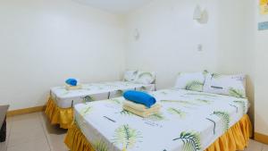 two beds in a room with white walls at Golden Success Hotel I by RedDoorz in Anao