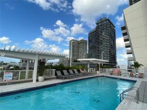 a large swimming pool with chairs and buildings at Wonderful 1 bedroom condo in Midtown. in Miami