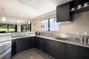 una cocina con armarios negros y encimeras de acero inoxidable en Pacific Escape - Downtown, Beach & Sea Views, en Mount Maunganui
