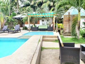 a swimming pool with chairs and a table next to a resort at Charisma Beach Resort in Siquijor