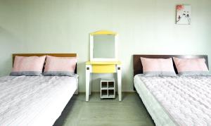 two beds in a room with a dresser and a mirror at Yeonhwachon Pension in Jeju