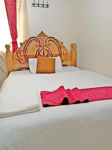 a bedroom with a white bed with a red blanket at Georgia Furnished Apartments in Machakos