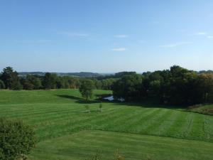 a large green field with a river in the middle at Woodlands Bed & Breakfast in Barnt Green