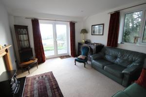 a living room with a couch and a desk and window at Woodlands Bed & Breakfast in Barnt Green