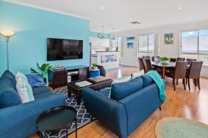 a living room with two blue couches and a dining room at SEArenity in Rosebud