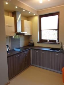 a large kitchen with brown cabinets and a window at Apartament "Rezydencja Park" w Mielnie in Mielno