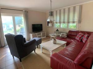 sala de estar con sofá rojo y TV en Top Lage! Charmantes Landhaus 5 Geh-Min v. Strand, en Timmendorfer Strand
