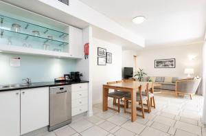 a kitchen and dining area with a table and a kitchen and a living room at Laguna on Hastings Noosa 127 in Noosa Heads