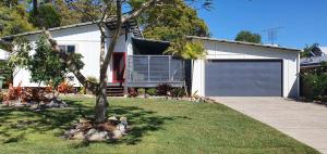 a house with a garage and a tree in the yard at Double 10 in Rainbow Beach