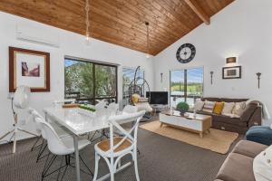 uma sala de estar com mesa e cadeiras em The Family Bach - Cable Bay Holiday Home em Cable Bay