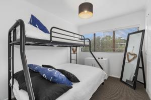 a bedroom with two bunk beds and a mirror at The Family Bach - Cable Bay Holiday Home in Cable Bay