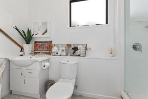 a bathroom with a toilet and a sink and a mirror at The Family Bach - Cable Bay Holiday Home in Cable Bay