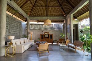 uma sala de estar com um sofá, mesas e cadeiras em Villa Amantes Bingin em Uluwatu