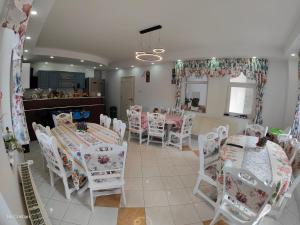 a dining room with white tables and white chairs at Pensiunea Nicolas in Sinaia