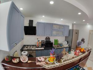 a kitchen with blue cabinets and a table with food on it at Pensiunea Nicolas in Sinaia
