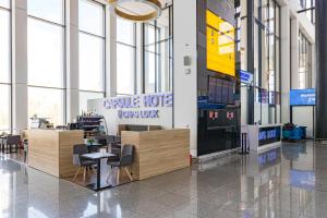 a lobby with tables and chairs in a building at CAPS LOCK Airport Hotel in Astana