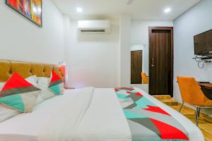 1 dormitorio con 1 cama grande y almohadas coloridas en FabExpress The Mall Inn, en Kānpur