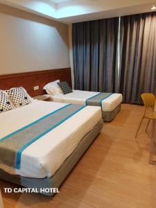 une chambre d'hôtel avec deux lits et une chaise dans l'établissement TD CAPITAL HOTEL, à Inanam