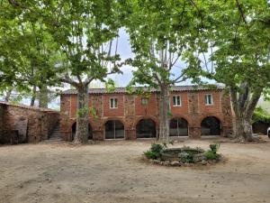 a large brick building with trees in front of it at Domaine de La Mayonnette in La Crau