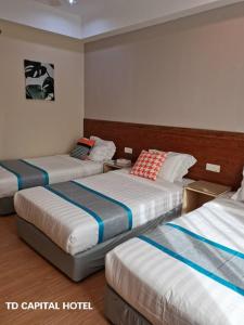 een hotelkamer met drie bedden in een kamer bij TD CAPITAL HOTEL in Inanam