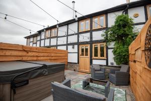 un patio trasero con una valla de madera y una casa en Bramble Cottage - Cosy 2 Bed With Deluxe HOT TUB & Log Burner, en Hereford