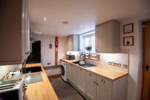 cocina con armarios blancos y encimera de madera en Bramble Cottage - Cosy 2 Bed With Deluxe HOT TUB & Log Burner, en Hereford