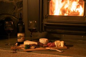 una mesa con copas de vino y queso y una chimenea en Washpen Falls en Windwhistle