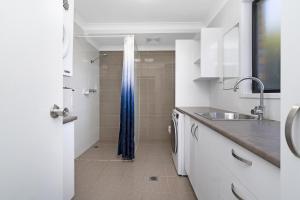 a bathroom with a sink and a shower with a blue shower curtain at Ammaboolah at Hat Head in Hat Head